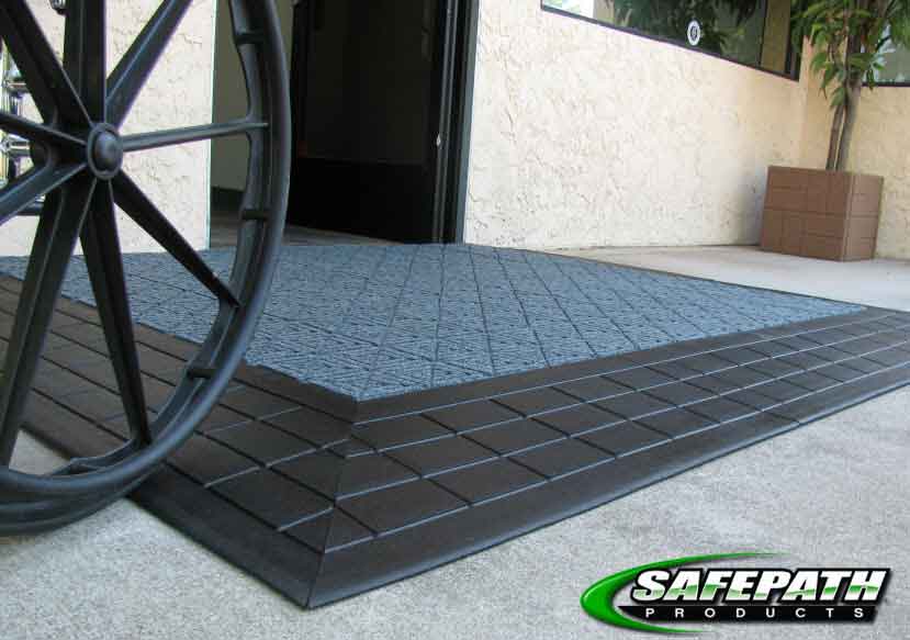 Wheelchair using an ADA compliant door threshold ramp and level landing to access a building
